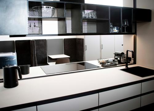 YokoLou - Design-Apartments في كوبلنز: مطبخ بأعلى كونتر أبيض ودواليب سوداء