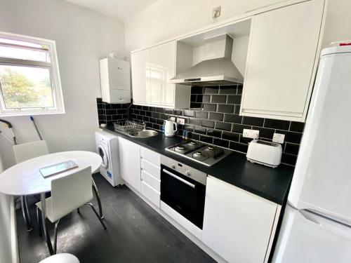 a kitchen with white cabinets and a black counter top at 1 Bedroom Apartment 3 mins walk Mile End Station in London