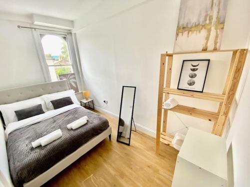 1 Bedroom Apartment 3 mins walk Mile End Station في لندن: غرفة نوم فيها سرير ومرآة