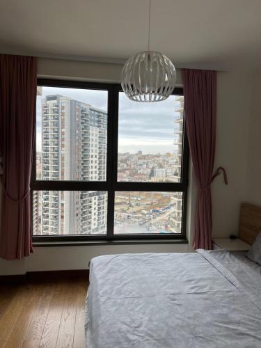 una camera da letto con una grande finestra con un lampadario a braccio di Belgrade Waterfront Premium a Belgrado