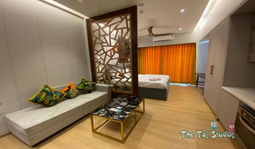 a room with a bed and a mirror and a couch at Taj Studios - Luxury Suit at Blue Sapphire Mall #US Cinema #PizzaHut #HIRA Sweets #Food Court etc by GHUMLOO-COM in Ghaziabad