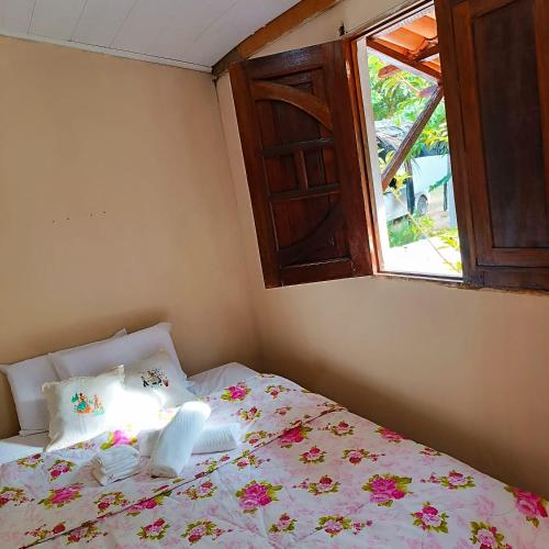 a bedroom with a bed with a window at Cantinho da Rosy in Maragogi