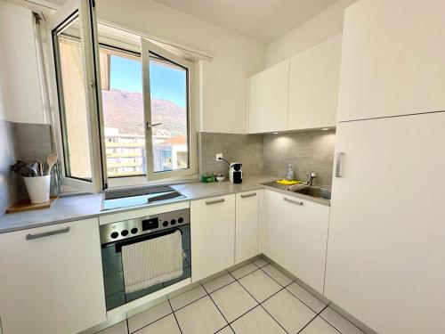 eine Küche mit weißen Schränken, einem Herd und einem Fenster in der Unterkunft Nuovo Appartamento con Vista! in Ascona