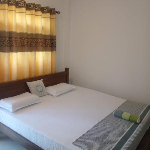 a bedroom with a large white bed with a window at Little Villa Guest House in Ahangama