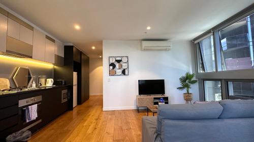 a living room with a blue couch and a tv at Nest Apartments on Rose Lane in Melbourne