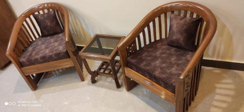 two wooden chairs and a table in a room at Casa Coutinho in Porvorim