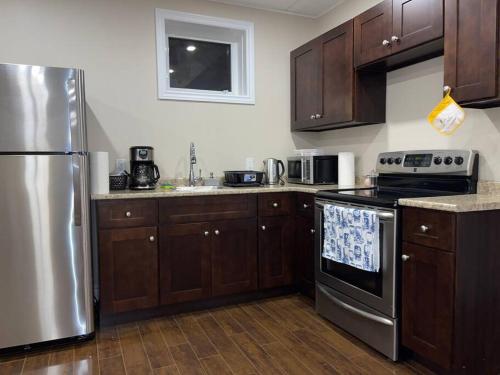 a kitchen with wooden cabinets and a stainless steel refrigerator at Gorgeous Apartment Serene Neighbourhood in Burlington