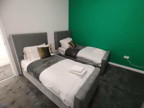 two beds in a room with a green wall at Adorable 2BR Apartment in The Rock Bury in Bury