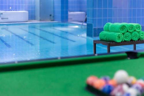 a swimming pool with green rolled towels on a table at City Tower Hotel in Kuwait