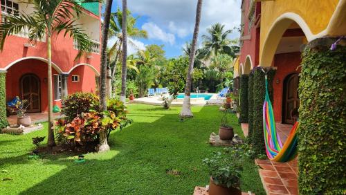 a resort yard with a pool and a surfboard at Casa Colonial, Cozumel in Cozumel