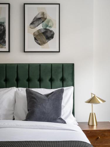 a bedroom with a green headboard and two framed pictures at Urban Rest Notting Hill Apartments in London