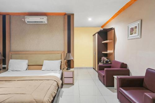 a bedroom with a bed and a couch and a chair at Collection O 93163 Hotel Grand Kartika in Parepare