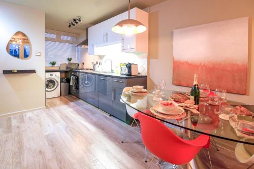 a kitchen with a glass table and red chairs at Sleeps 5 - King bed 2WC - Limehouse DLR Central E1 in London