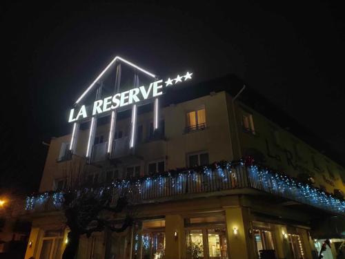een gebouw met 's nachts een verlicht bord bij Hôtel La Réserve in Gérardmer