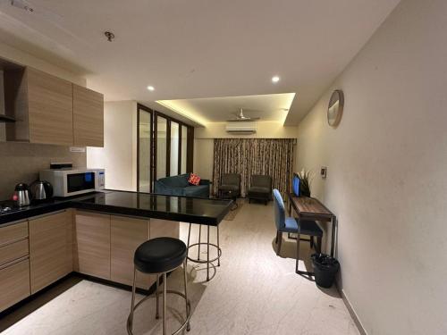 1.5BR Service apartment in BKC by Florastays في مومباي: مطبخ مع كونتر وكراسي في غرفة