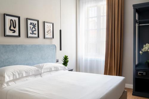 フィレンツェにあるFlom Boutique Hotelの白いベッドと窓のある寝室