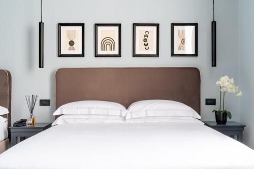 ein Schlafzimmer mit einem weißen Bett mit vier Bildern an der Wand in der Unterkunft Flom Boutique Hotel in Florenz