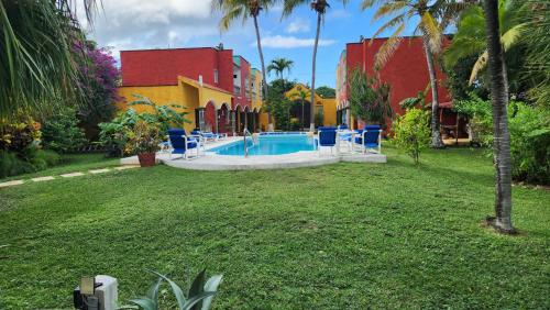 a swimming pool in a yard with blue chairs at Casa Colonial, Cozumel in Cozumel