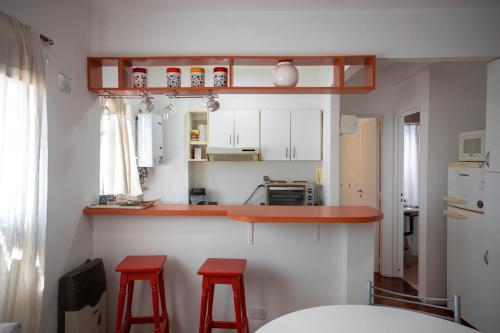 una cocina con 2 taburetes rojos y una barra en Dos ambientes en Palermo (La Rural) en Buenos Aires