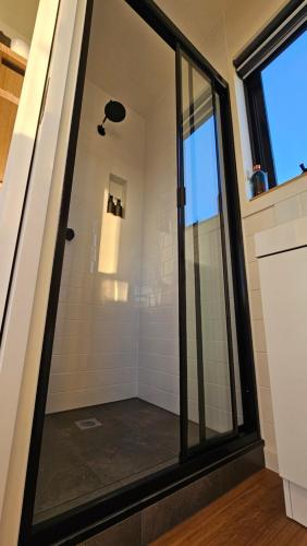 a shower with a glass door in a bathroom at Sunset Haven - port fairy tiny homes in Killarney