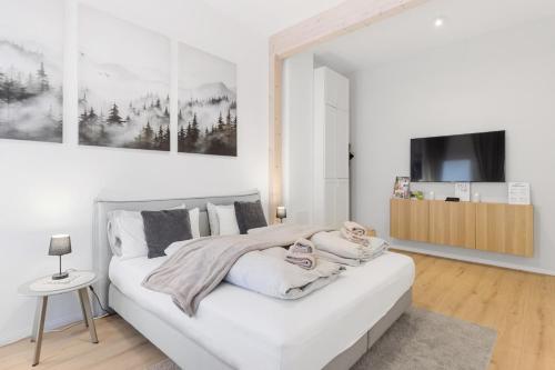 a white bedroom with a large white bed and a tv at Stilvolles City-Apartment - Pfalzliebe Suites in Landau in der Pfalz