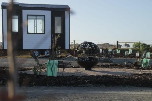 a group of benches and a sculpture in front of a house at Coastal Haven Tiny Home - Port Fairy Tiny Homes in Killarney
