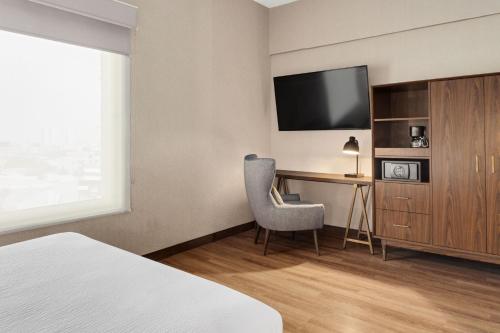 a hotel room with a bed and a desk with a television at Four Points by Sheraton Galerias Monterrey in Monterrey