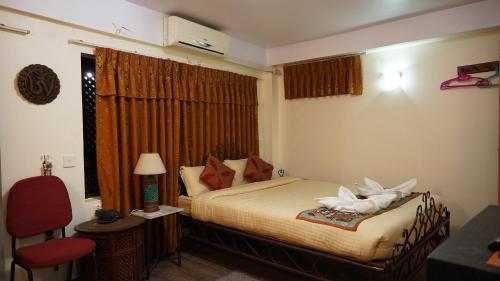 a bedroom with a bed and a red chair at Cosy Hotel in Bhaktapur