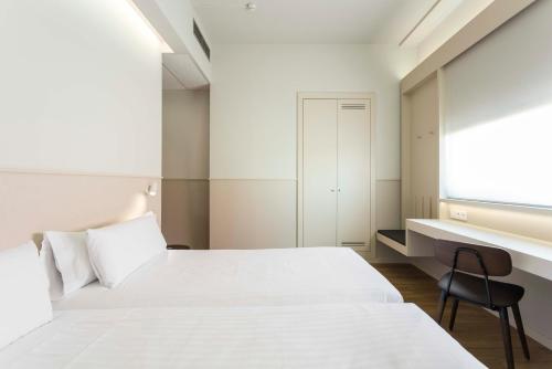1 dormitorio con cama blanca y escritorio en Hotel Terrassa Confort, en Terrassa