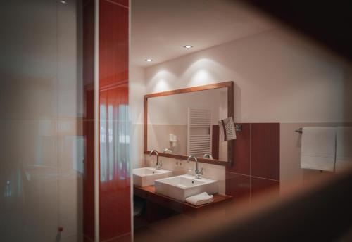 a bathroom with two sinks and a large mirror at Hotel Sonnenhof in Castelrotto