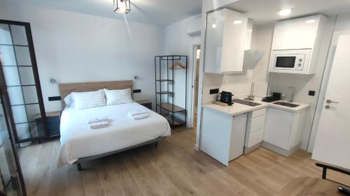 a bedroom with a white bed and a kitchen at MiRa San Basilio in Córdoba