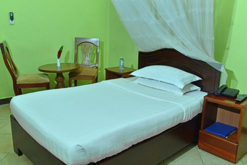 a bedroom with a bed and two chairs and a table at JEVINE HOTEL in Kampala