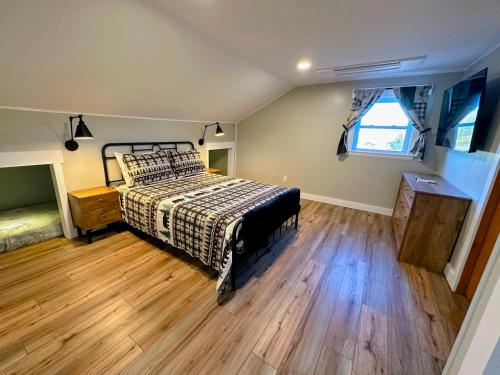 1 dormitorio con 1 cama y suelo de madera en Renovated farmhouse on snowmobile trail with firepit & mountain views, 10 min from Bretton Woods!, en Twin Mountain