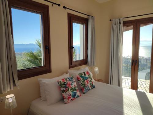 a bedroom with two windows and a bed with pillows at Sun Touch Pelion Rooms in Kala Nera