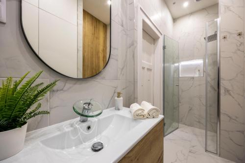 La salle de bains blanche est pourvue d'un lavabo et d'un miroir. dans l'établissement Luxurious Central 4BEDRM 3BATHRM Residence w/ Balcony, à Budapest