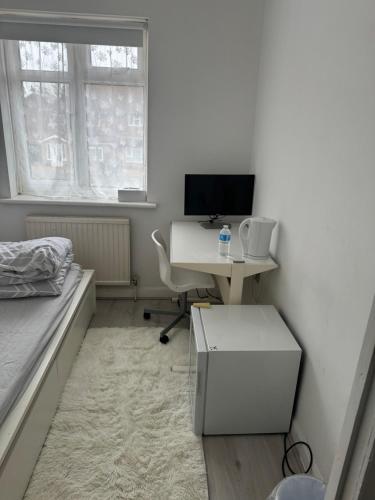 a bedroom with a desk with a computer and a bed at Single Room in Canvey