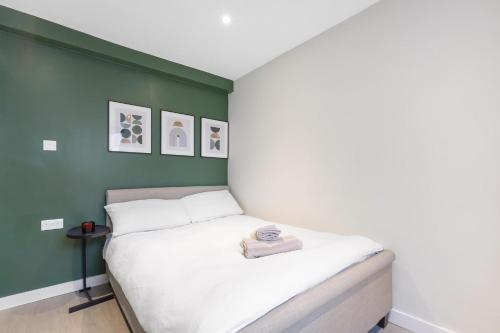 a bed in a room with a green wall at Quaint Mews Home in Chelsea in London