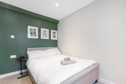 a bed in a room with a green wall at Quaint Homes in Chelsea in London