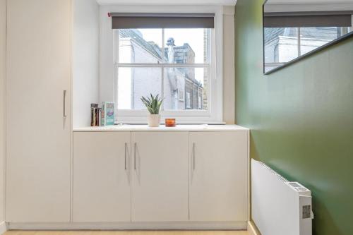 a white cabinet in a room with a window at Quaint Mews Home in Chelsea in London