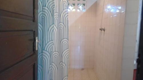 uma casa de banho com um chuveiro com azulejos azuis e brancos em Les Datchi Cottages em Diani Beach