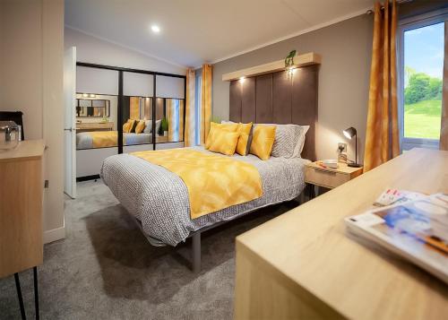 a bedroom with a bed with yellow sheets and a window at Sandgreen Caravan Park in Girthon