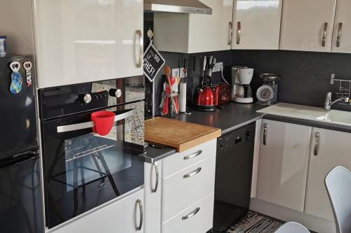 a kitchen with white cabinets and a black refrigerator at Villa avec tout le confort dans le livradois forez 