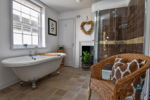 bagno con vasca, finestra e sedia di The Georgian House a Weymouth