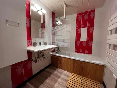 y baño con lavabo, bañera y azulejos rojos y blancos. en Gite "Les Essis", en Gérardmer