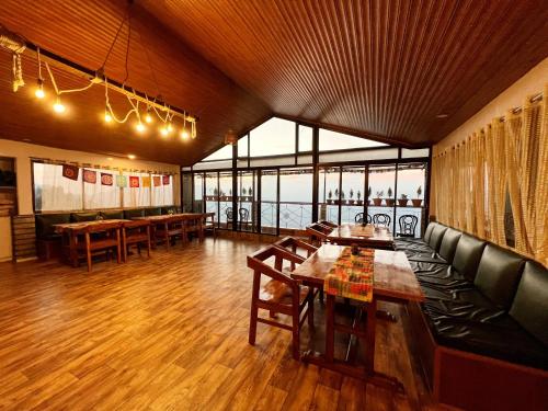 a restaurant with tables and a couch and windows at Darjeeling Heights - A Boutique Mountain View Homestay in Darjeeling