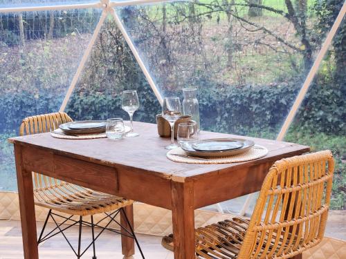 - une table en bois avec des verres et des assiettes dans l'établissement Dôme magnifique avec spa, à La Chapelle-du-Fest