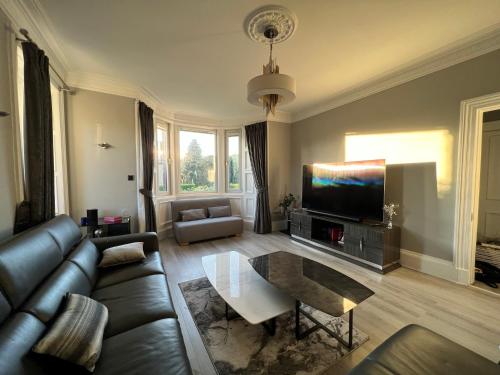 a living room with a couch and a tv at Immanuel House - Modern Luxury Victorian Home 1872 - Free Parking & SuperFast Fibre Optic WiFi in Edinburgh