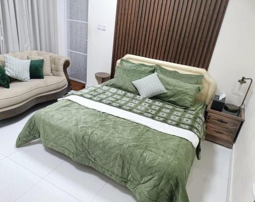 a bedroom with a green bed and a couch at alshahad chalet in Bārsit