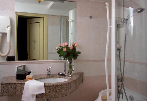a bathroom with a sink with a mirror and a vase of flowers at Cà Rialto in Venice