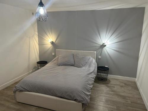 a bedroom with a bed with two lights on the wall at Appartement au cœur du Berry in Lignières